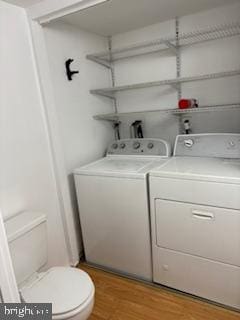 laundry area featuring washing machine and clothes dryer and light wood-type flooring