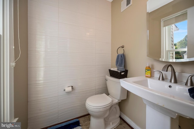 bathroom featuring tile walls, sink, and toilet