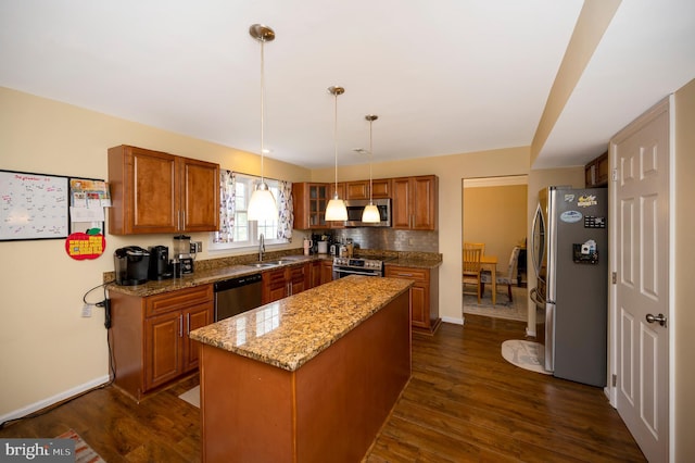 kitchen with dark hardwood / wood-style flooring, appliances with stainless steel finishes, light stone countertops, decorative light fixtures, and a center island