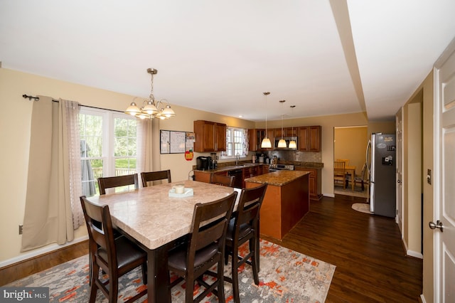 dining area with sink, a chandelier, a healthy amount of sunlight, and dark hardwood / wood-style flooring