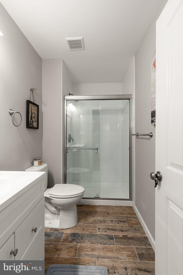 bathroom with wood-type flooring, vanity, toilet, and an enclosed shower