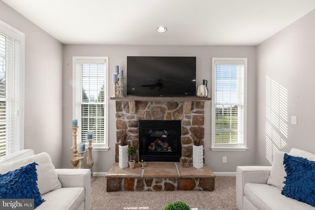 carpeted living room featuring a healthy amount of sunlight and a stone fireplace