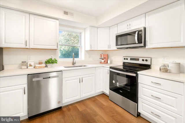 kitchen with white cabinets, light hardwood / wood-style floors, sink, and stainless steel appliances