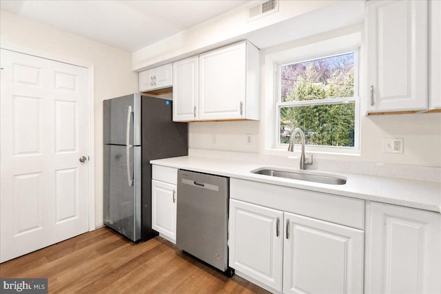 kitchen featuring white cabinets, stainless steel appliances, light hardwood / wood-style floors, and sink