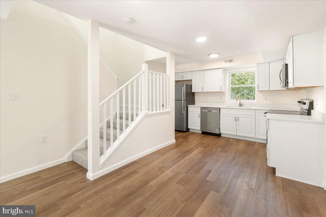 kitchen with hardwood / wood-style floors, white cabinetry, sink, and appliances with stainless steel finishes