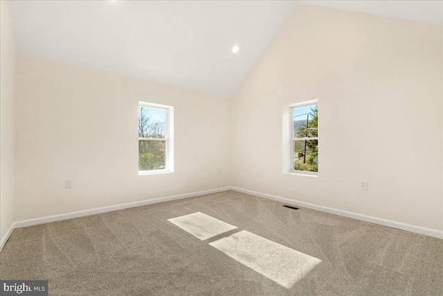 carpeted spare room with high vaulted ceiling