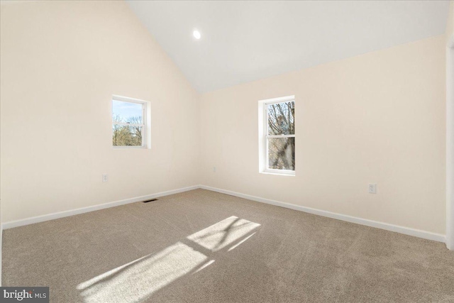 carpeted empty room with high vaulted ceiling