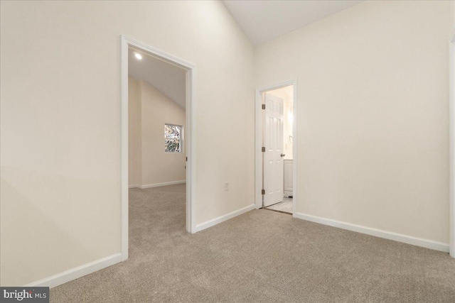 unfurnished room featuring light colored carpet and vaulted ceiling