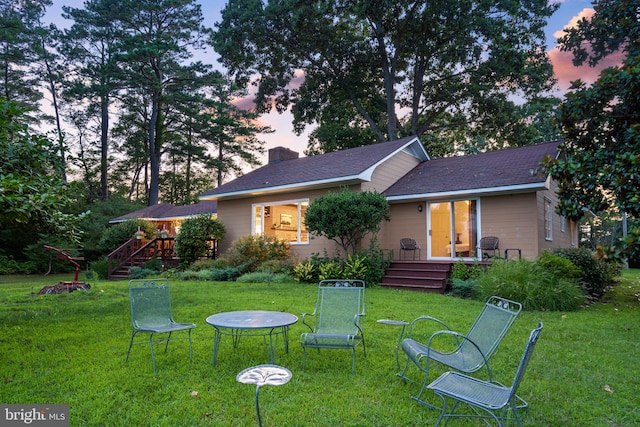 back house at dusk featuring a yard