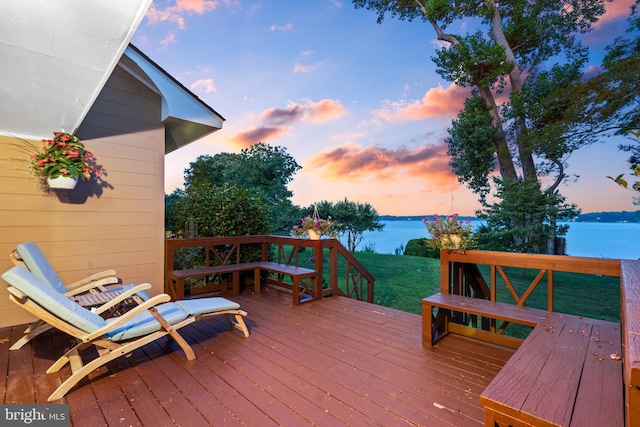 deck at dusk featuring a yard and a water view