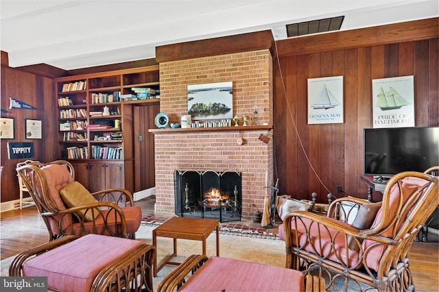 living room with a fireplace, hardwood / wood-style flooring, and wood walls