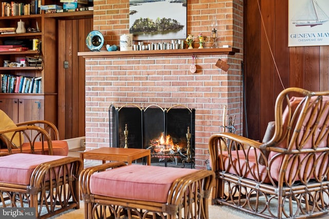 living area featuring wood walls, carpet, and a fireplace