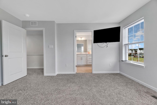 unfurnished bedroom featuring ensuite bathroom and carpet