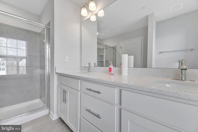 bathroom featuring vanity, a shower with shower door, and tile patterned flooring