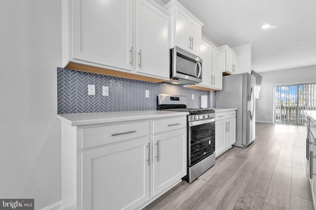 kitchen featuring backsplash, appliances with stainless steel finishes, light hardwood / wood-style flooring, and white cabinets