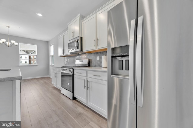 kitchen featuring white cabinetry, a chandelier, light wood-type flooring, decorative light fixtures, and stainless steel appliances