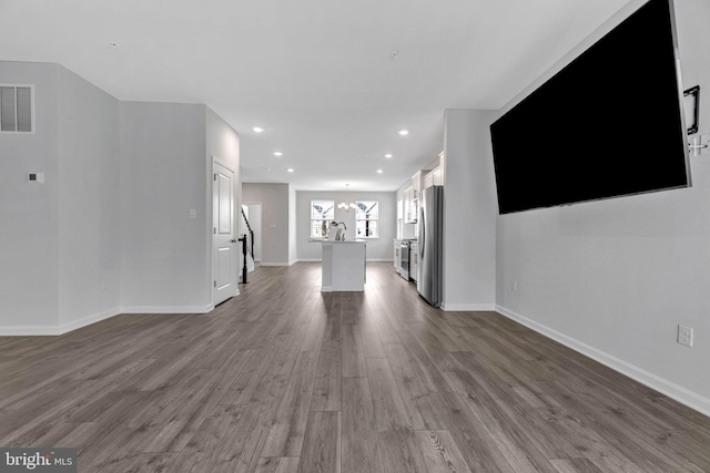 unfurnished living room with hardwood / wood-style flooring and an inviting chandelier