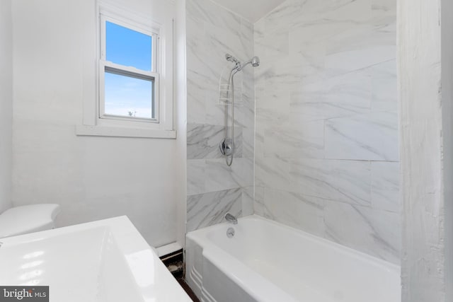 bathroom with toilet and tiled shower / bath combo