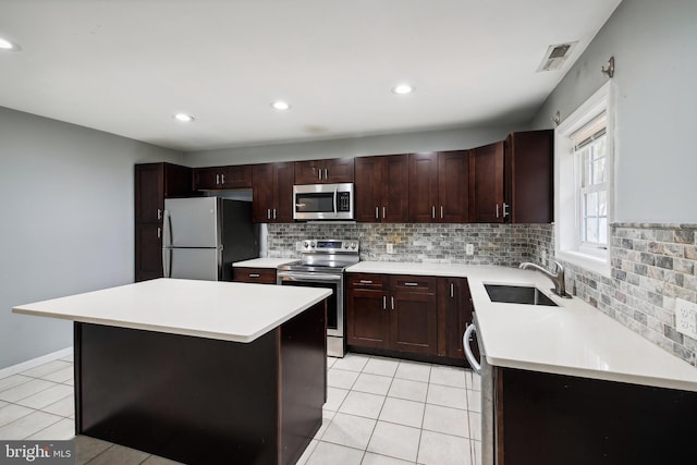 kitchen featuring a kitchen island, appliances with stainless steel finishes, sink, and light tile patterned flooring