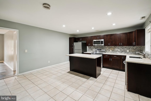 kitchen featuring stainless steel appliances, sink, tasteful backsplash, light tile patterned floors, and a kitchen island