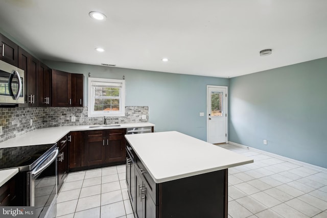 kitchen with stainless steel appliances, sink, tasteful backsplash, light tile patterned flooring, and a kitchen island