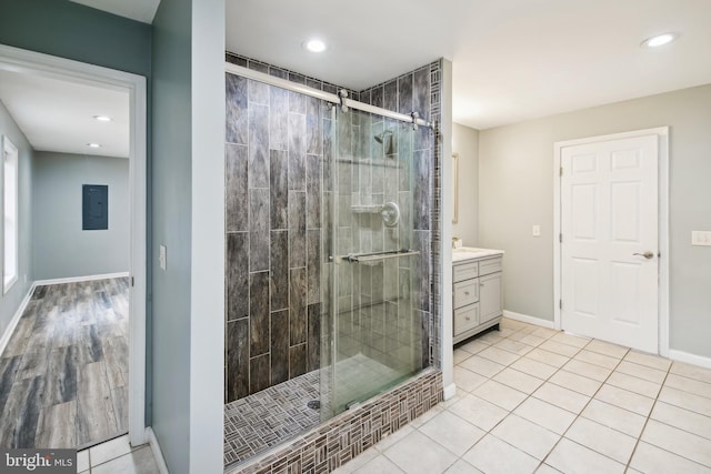 bathroom with walk in shower, tile patterned flooring, vanity, and electric panel