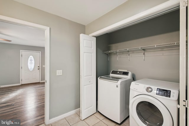 clothes washing area with washing machine and dryer, ceiling fan, and light hardwood / wood-style flooring