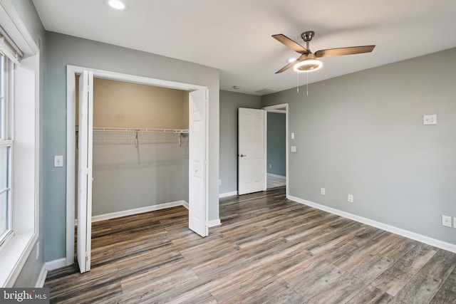 unfurnished bedroom with hardwood / wood-style flooring, multiple windows, ceiling fan, and a closet