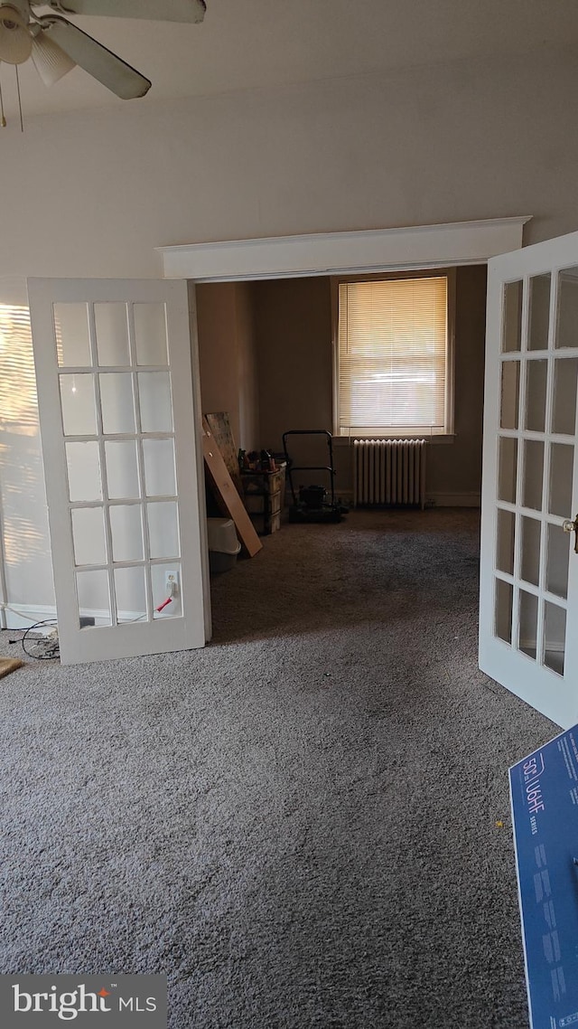 spare room featuring radiator heating unit, carpet, and ceiling fan