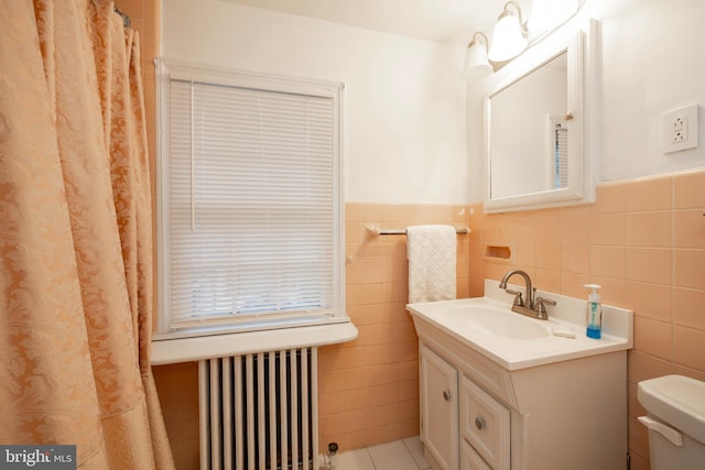 bathroom featuring tile walls, vanity, toilet, and radiator