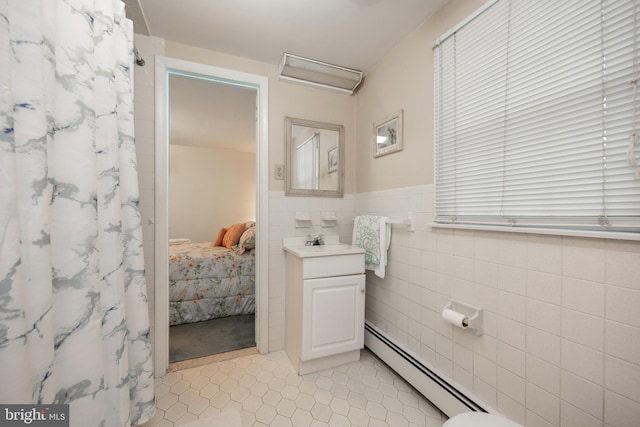 bathroom featuring tile patterned flooring, tile walls, baseboard heating, and vanity