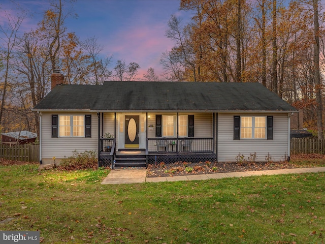 ranch-style home with a lawn and covered porch