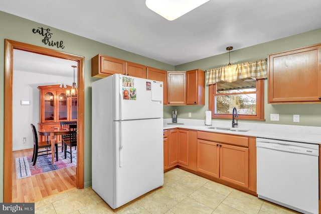 kitchen featuring a notable chandelier, hanging light fixtures, sink, white appliances, and light hardwood / wood-style flooring