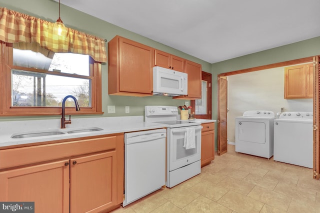 kitchen featuring washer and clothes dryer, hanging light fixtures, sink, and white appliances