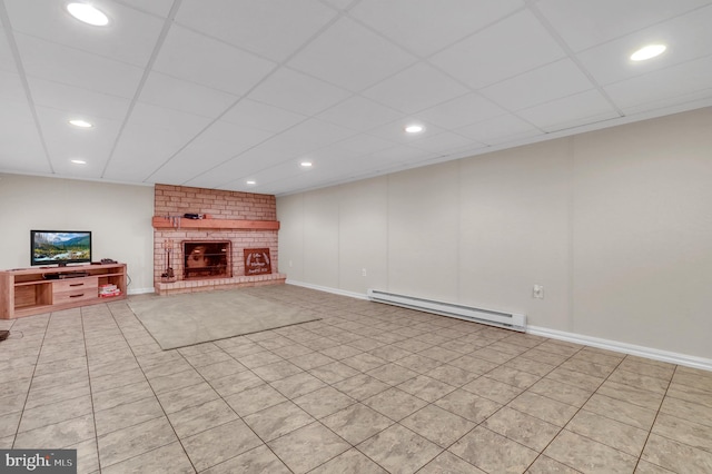 unfurnished living room featuring a drop ceiling, baseboard heating, light tile patterned floors, and a brick fireplace