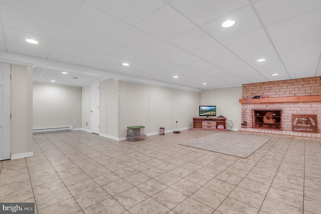 basement with a fireplace, light tile patterned flooring, baseboard heating, and a paneled ceiling