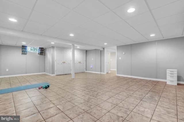 basement with a paneled ceiling and light tile patterned floors