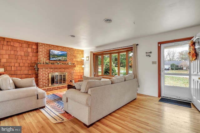 living room with light wood-type flooring and a brick fireplace