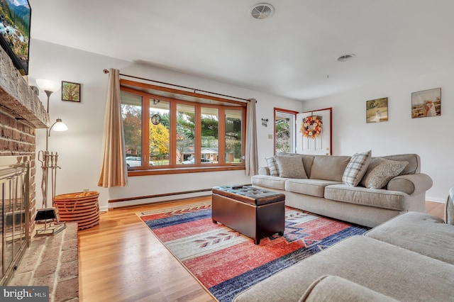 living room with a brick fireplace, hardwood / wood-style floors, and a baseboard radiator