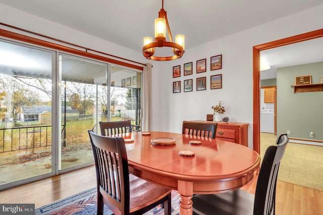 dining room featuring light hardwood / wood-style floors, washer / dryer, and a notable chandelier