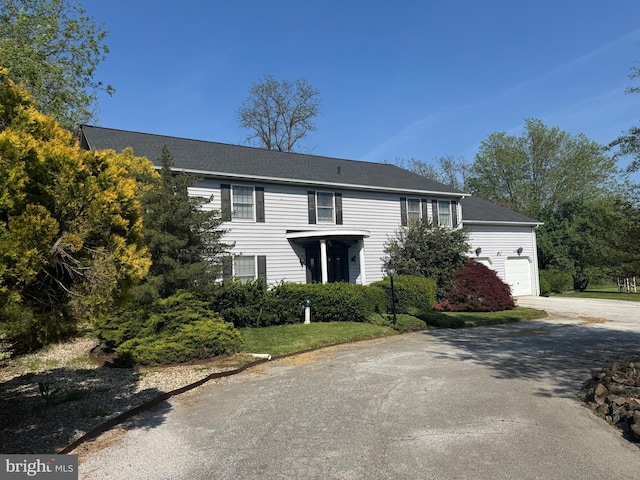 colonial house with an attached garage and aphalt driveway