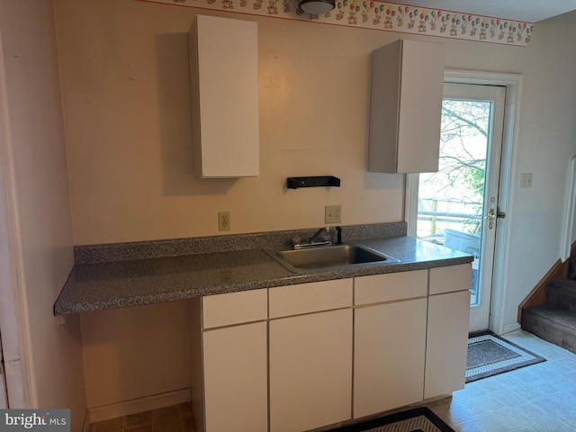 kitchen with white cabinetry, dark countertops, and a sink