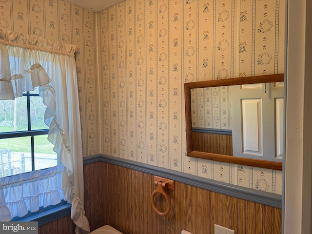 bathroom featuring wallpapered walls and wainscoting