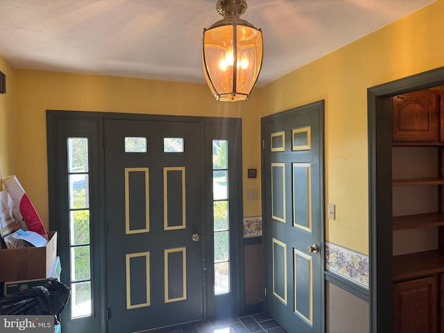 tiled entryway featuring an inviting chandelier and plenty of natural light