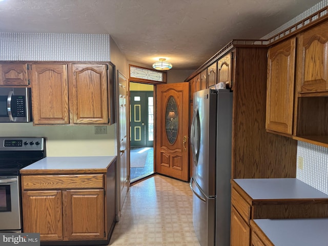 kitchen featuring light floors, stainless steel appliances, light countertops, and brown cabinets
