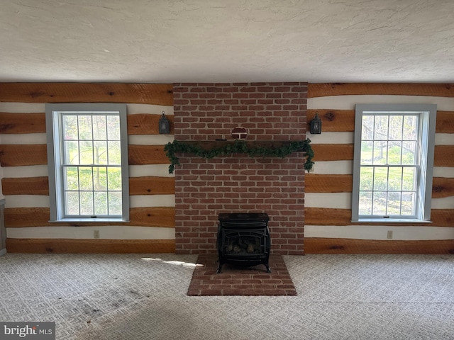 unfurnished living room with baseboards, a wood stove, a healthy amount of sunlight, and carpet floors