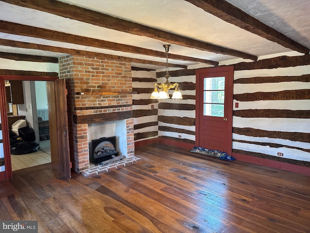 unfurnished living room featuring beam ceiling, dark wood-type flooring, wood walls, and a notable chandelier