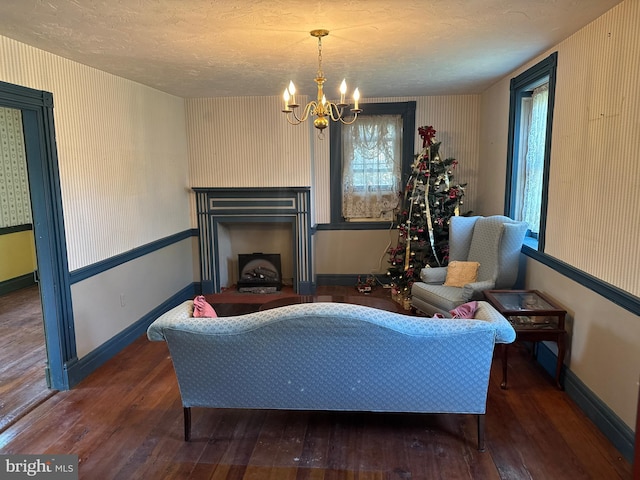 living area with a textured ceiling, a fireplace, hardwood / wood-style floors, and a notable chandelier