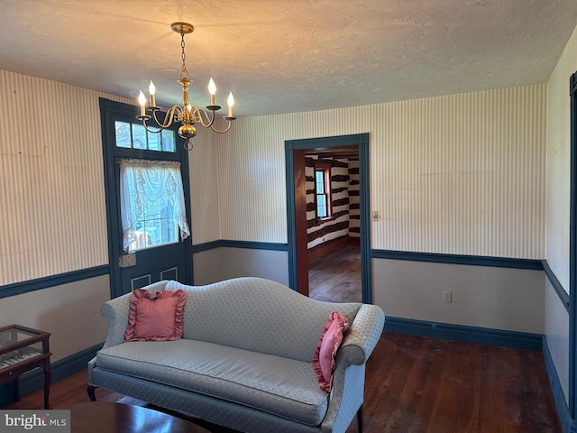 sitting room featuring a textured ceiling, a chandelier, baseboards, and hardwood / wood-style flooring