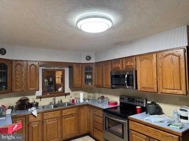 kitchen with stainless steel appliances, a textured ceiling, and sink